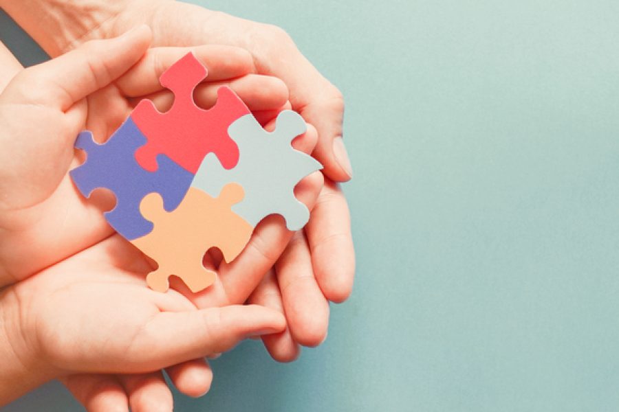 Adult and chiild hands holding jigsaw puzzle shape, Autism awareness, Autism spectrum family support concept, World Autism Awareness Day