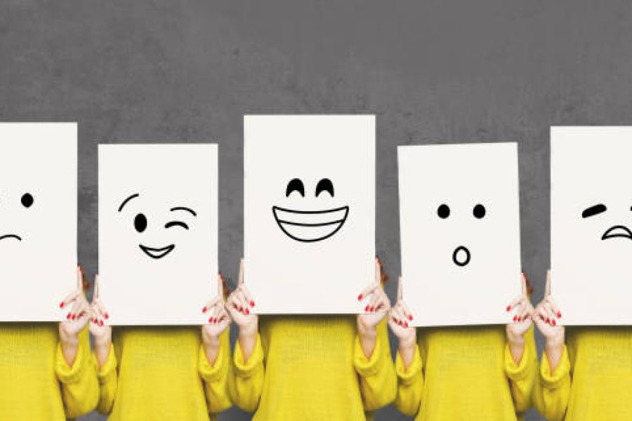 Emotions set. Girl hiding face behind signboard with drawn smileys. Collage of indifferent, winking, happy, surprised, and sad emoticons.